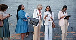 Women, diverse and business or standing waiting cellphone, paperwork or corporate employees talking. Female people, line or delay for company work or outdoor brick wall, tablet communication or staff