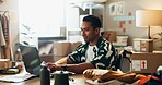 Laptop, fashion and ecommerce with a man in a wheelchair at work in a studio for delivery or product shipping. Computer, supply chain logistics and a young person with a disability in a workshop