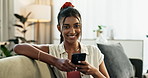 Woman, phone and face with smile on sofa for communication, typing or email in living room of home. Indian, person or portrait or smartphone for texting with internet or technology on couch in lounge