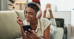 Woman, phone and headphones for singing on sofa, smile and relax with music, sound and mobile app. Girl, smartphone and audio streaming subscription for dance, listening and funny on lounge couch