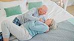 Love, happy and senior couple on bed with romance, bonding and relaxing together at home. Smile, kissing and elderly man and woman in retirement laying in bedroom of modern house or apartment.