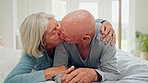 Senior, hug and couple kiss in bed, care and bonding together in home. Love, happy elderly man and woman in bedroom for connection, support and healthy relationship, romance and relax in retirement