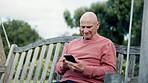 Nature, phone and senior man on a bench networking on social media, mobile app or the internet. Happy, technology and elderly person in retirement scroll on website with cellphone on swing in garden.