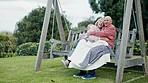 Nature, blanket and senior couple on a bench hugging, bonding and cuddle together in garden. Happy, love and elderly man and woman in retirement embracing and sitting on wood swing in outdoor park.