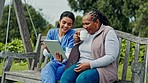 Happy woman, nurse and patient with tablet on park bench or swing in relax, entertainment or nature. Female person or medical caregiver sitting outdoor with senior, technology or coffee for support