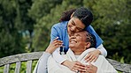 Happy woman, nurse and patient hug on park bench in elderly care, healthcare or support in nature. Female person smile helping in outdoor nursing with blanket, love or trust for retirement in garden