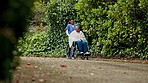 Woman, nurse and patient walking with wheelchair in nature for outdoor healthcare, support or trust. Female doctor or medical caregiver pushing person with a disability in elderly care or nursing