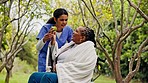 Caregiver, senior woman and park with wellness, apple and conversation in the garden. Fruit, health discussion and nurse with elderly female person with speaking and food with patient in nature