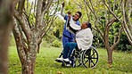 Happy woman, nurse and patient by tree in wheelchair for support, outdoor healthcare or trust in nature. Female doctor or medical caregiver helping person with a disability in elderly care or nursing