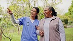 Senior care, old woman and nurse pointing in garden in support, help or trust at nursing home backyard. Smile, retirement healthcare and happy elderly person with caregiver walking on grass together.