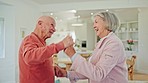 Senior couple, dancing and happy in home with smile for love, romance or bonding for wellness in retirement. Elderly woman, old man and together in kitchen for steps, moving or holding hands in house