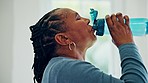 Senior woman, drinking water and bottle with yoga mat for hydration, electrolytes and wellness in home. Elderly African lady, training and exercise for health with detox, nutrition and diet in house