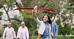 Airplane, playing and child in park with parents for holiday, vacation and weekend outdoors with toys. Happy, family and girl with plane, mom and dad in nature for freedom, adventure and running