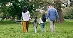 Family, park and parents walking with children for bonding, relationship and holding hands outdoors. Nature, back and mom, dad and kids on holiday, vacation and weekend for relax, fun and adventure