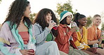 Friends, group or drinking juice outdoor with communication, story or gossip in summer for bonding or happiness. People, girls or sitting on a park with conversation, diversity and laughing in nature