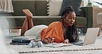 Laptop, laying and woman writing notes on the floor in the living room of modern apartment. Technology, research and young African female university student studying on a computer in lounge at home.