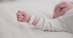 Baby, new born and hand with bracelet on bed for care, trust or support in hospital for birth. Infant, love and hope with child development for future growth in family home, protection and security