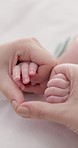 Heart, family and holding hands with baby on bed for bonding, love and relationship at home. Adorable, cute and closeup of parent with newborn infant for support, child care and protection at home