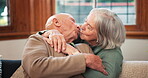 Senior, couple and surprise hug for kiss on sofa, marriage and care for support in living room. Elderly man, woman or happy with relax, retirement bonding or smile together in embrace in family home