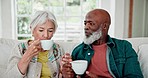 Elderly couple, diveristy and coffee with communication on sofa, marriage and care for support in living room. Elderly man, woman or love with relax, retirement or smile together for espresso in home