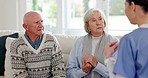 Healthcare, appointment and a nurse talking to an old couple on a sofa in the living room of their home. Medical, checkup or apartment visit with a senior man and woman speaking to a young caregiver