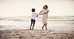 Family, beach and a mother dancing with her son on the sand together by the ocean or sea at sunset. Energy, freedom and a black woman having fun with her boy child in nature on holiday or vacation