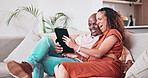 Smile, tablet and funny couple on sofa in home, communication and watch comedy movie, video or meme. Interracial man, woman and laugh on technology, relax on couch and social media app in living room