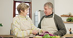 Senior woman, man and kitchen with vegetables, cooking and knife with conversation for health, diet and food. Couple, retirement and happy with leaves, pepper and nutrition for wellness in house