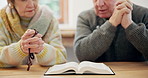 Hands, bible and senior couple praying for faith, worship and praise Jesus Christ, holy spirit and God at home. Closeup, rosary and reading books for christian prayer, gratitude or spiritual religion