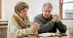 Senior couple, home and bible for praying, faith and worship Jesus Christ, holy spirit and God. Man, woman and hands together for christian prayer, spiritual religion and gospel books in retirement 