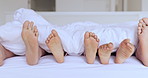 Family, bed and feet together in closeup, kids and play in home with sheet, hospitality or comfort with bonding. People, children and bedroom with toes, blanket and sole to relax, holiday or vacation
