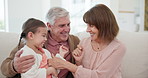 Grandparents, child and play with smile, home and embrace with love, grandchild and couch. Man, woman and lounge or bonding together for relationship, family and retired with girl, house and kid
