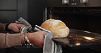 Family, baking and the hands of a father with his son in the kitchen to remove fresh bread from the oven. Kids, love and a dad teaching his boy child hot to bake while cooking in their apartment