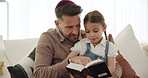 Reading, book and father with girl in home, teaching and learning about Torah, religion and spiritual knowledge. Child, education and sharing Jewish gospel, faith and culture history on sofa together