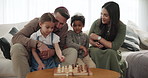 Parents, children and chess play in home for game in Jewish family, learning strategy or competition. Mother, father or siblings support or together time event, skill development or parent connection