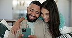 Love, hug and couple on a sofa with phone happy, care and bond in their home together. Smile, face and people embrace in a living room with smartphone for social media, communication or streaming app