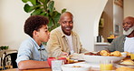 Happy, black family and child at table for lunch, supper and eating meal at home together. Grandparents, parents and young boy with food for bonding, relax and talking in dining room for nutrition