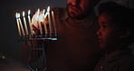 Jewish, religion and a family lighting candles together in their home for Hanukkah celebration. Culture, holiday or tradition with a father and son closeup in the dark for their faith or belief