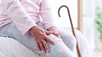 Walking stick, knee and senior woman with disability, home and massage for recovery, arthritis or injury. Hands, elderly person and rehabilitation for mobility, joint and muscle pain in bedroom