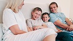 Happy, laughing and parents with children in the bed talking, bonding and having fun together. Smile, happiness and young mother and father relaxing with boy kids in bedroom of modern family home.