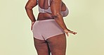 Dancing, body positivity and butt of woman in underwear in a studio for self love celebration. Health, wellness and bum of young African female model moving with confidence by green background.