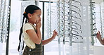 Optometry, store and girl with options, decision and retail with clear vision, prescription lenses and choose. Person, kid and child with eyewear, shopping and customer with thinking, frame or client