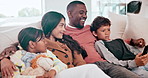 Happy, smile and family watching a movie on a sofa in the living room of modern family home. Laughing, entertainment and young children relaxing and streaming show with interracial mother and father.