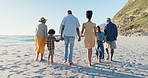 Beach, back and big family holding hands while walking in nature for travel, love or freedom. Rear view, support and kids with parents and grandparents at the ocean for summer, vacation or adventure
