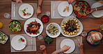 Above, food and hands for lunch on table with community, dining room for friends together in home. Health, cooking and salad with meat for event, healthy nutrition for group of people on vacation 