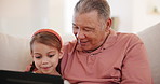Smile, tablet and grandfather with child on a sofa in living room networking on internet in family home. Happy, love and senior man in retirement bond, relax and scroll on digital technology with kid