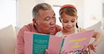 Happy, book and grandfather reading with kid on a sofa in the living room of family home. Smile, love and senior man in retirement bonding, relaxing and enjoying a story with girl child in the lounge