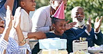 Birthday, applause and a girl blowing candles on a cake outdoor with her family for celebration at a party. Kids, love or smile and a black child clapping in the garden together with her grandparents