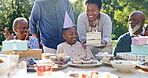 Child, happy birthday and blows candles in outdoor celebration, party and cake or singing at park. Black family, happiness and support for son, cheers and event or together, garden and food or love