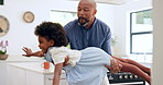 Black family, flying and a girl in the arms of her father for love in the kitchen of their home together. Smile, fantasy plane or imagination games with a man parent and girl child in their apartment